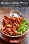 A basket of broiled buffalo wings with celery sticks and blue cheese dressing.