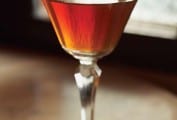 A classic Manhattan cocktail in a coupe glass with a lemon garnish.