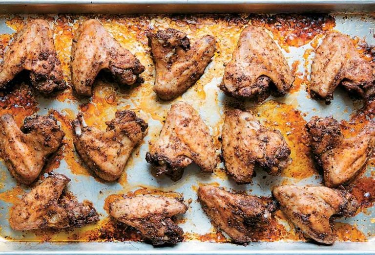 A rimmed baking sheet filled with peppery chicken wings