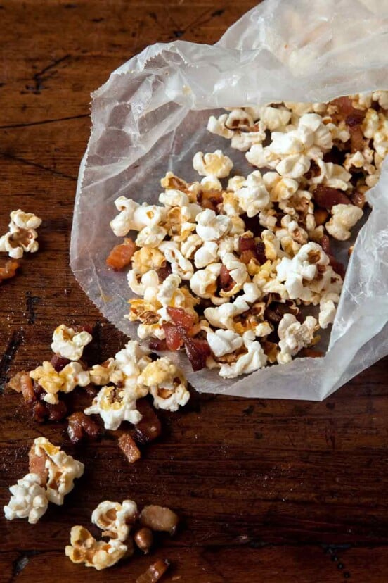 Open waxed paper bag with popcorn and maple bacon bits spilling out