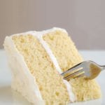 A wedge of classic white cake and white frosting with a fork cutting in