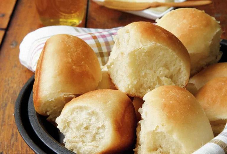 A bowl lined with a napkin and filled with pull-apart rolls.