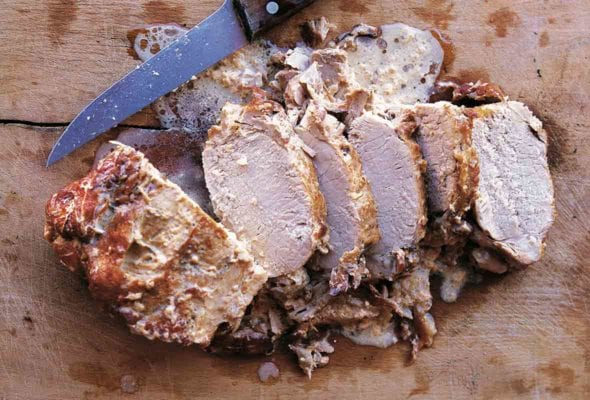 The classic Italian dish: roast pork cooked in milk, maiale al latte, sliced on a cutting board.