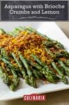 Asparagus with brioche crumbs piled on a white serving platter.