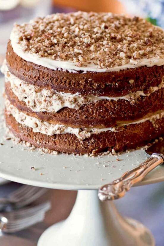 A three-layer hummingbird cake with a cake server beside it.