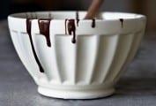 Melted chocolate in a white bowl with a wooden spoon