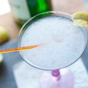 En frusen gin-fizz i ett martiniglas med en apelsinrörasticka och en liten bit citron på kanten.