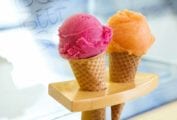 Two sugar cones, one filled with a scoop of cantaloupe sorbet, the other with a scoop of hibiscus beet sorbet.