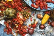 A newspaper-topped table strewn with crawfish, corn, peppers, and potatoes - a classic crawfish boil.