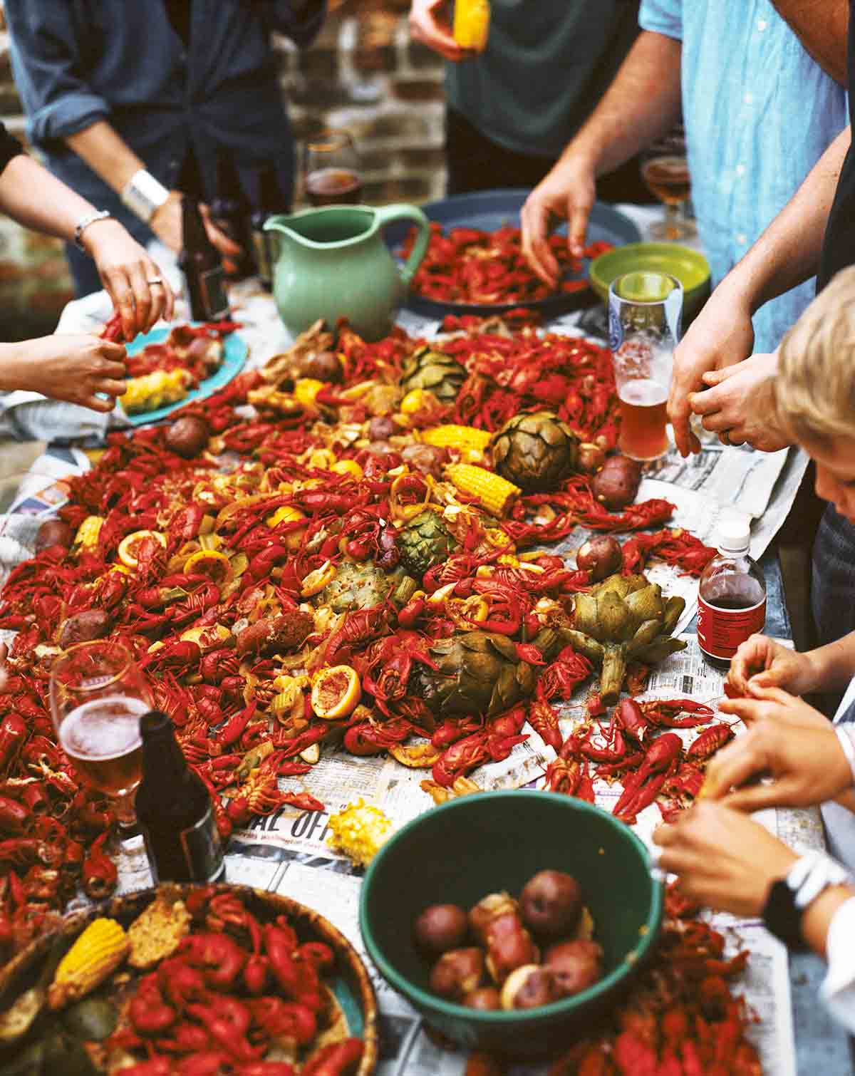 A newspaper-topped table strewn with crawfish, corn, peppers, and potatoes - a classic crawfish boil.
