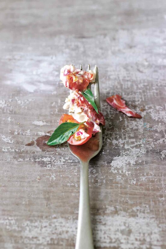 Fork with lobster salad and tomato salad, two small leaves of basil