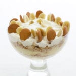 Big glass bowl of layers of vanilla wafer banana pudding topped with sliced bananas, Nilla wafers, and whipped cream
