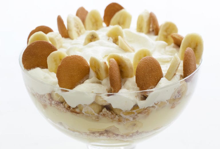 Big glass bowl of layers of vanilla wafer banana pudding topped with sliced bananas, Nilla wafers, and whipped cream