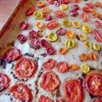 A rimmed baking sheet filled with assorted oven-roasted tomatoes.