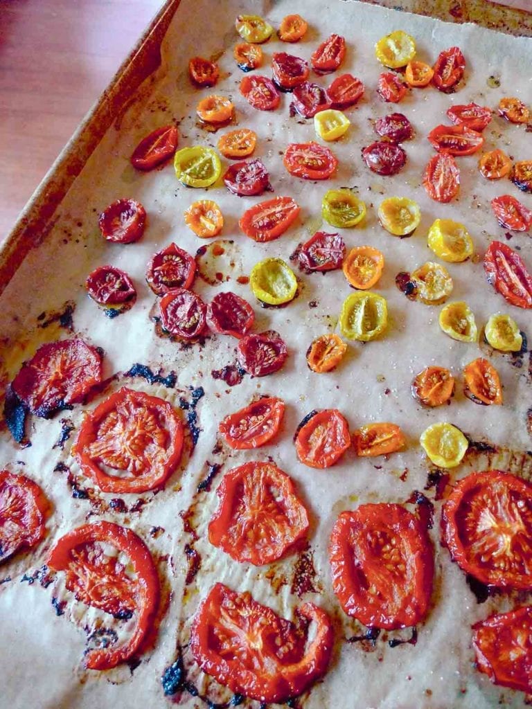 A rimmed baking sheet filled with assorted oven-roasted tomatoes.