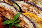Layers of zucchini, summer squash, and eggplant cooked together and garnished with basil for this summer vegetable gratin.