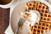 A waffle topped with salted caramel sauce on a white plate