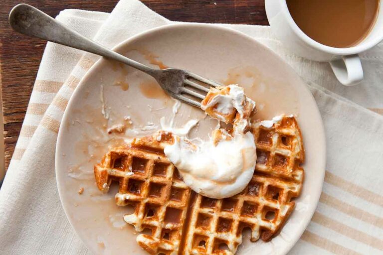 A waffle topped with salted caramel sauce on a white plate