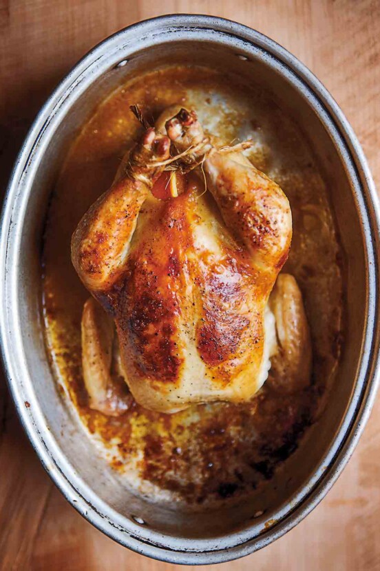 A whole cooked wheat beer roasted chicken in a deep oval baking dish.