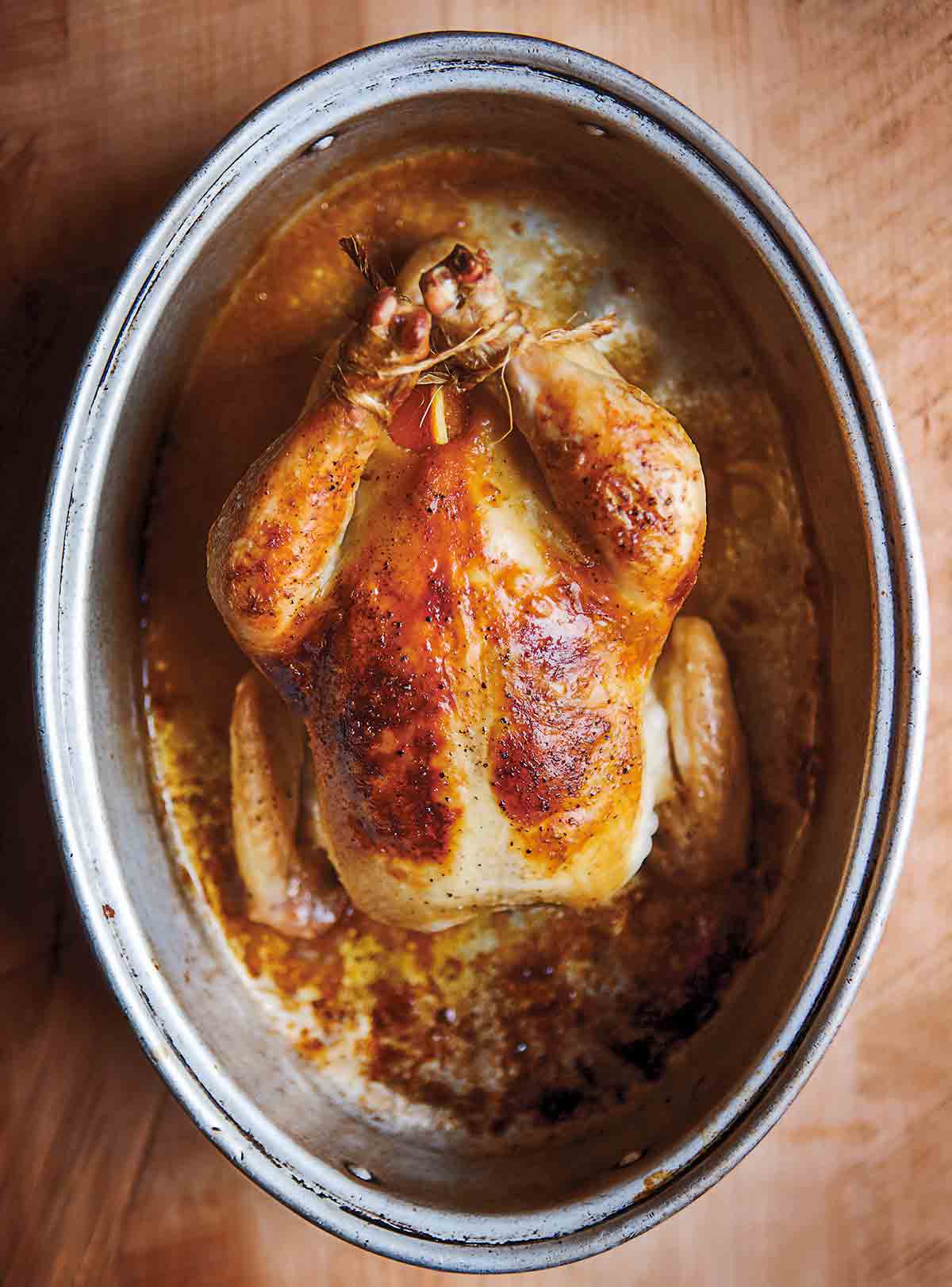 A whole cooked wheat beer roasted chicken in a deep oval baking dish.
