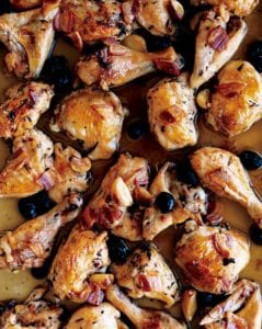 Tray of roast chicken pieces with pancetta, olives, and garlic cloves.