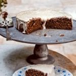 A cut root beer cake on a pewter platter with a slice on a decorative plate in front.