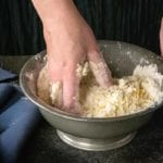 Shortcut pie crust being mixed together by hand in a bowl.