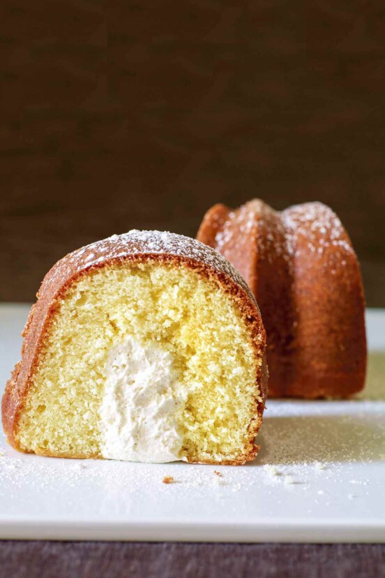 A slice of twinkie bundt cake dusted with confectioners' sugar and turned to show the cross section.