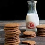 Three stacks of gingersnaps, one broken cookie, and a glass bottle of milk