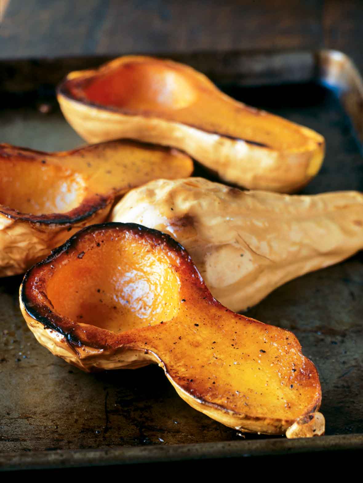 Four halves of butternut brown butter winter squash on a rimmed baking sheet.