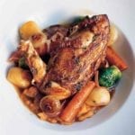 A large white serving bowl filled with chicken with autumn vegetables and Madeira wine.