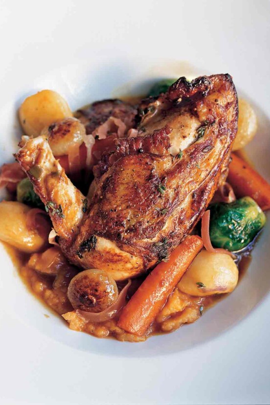 A large white serving bowl filled with chicken with autumn vegetables and Madeira wine.