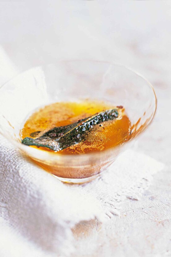 Sage brown butter with a crispy sage leaf in a small glass.