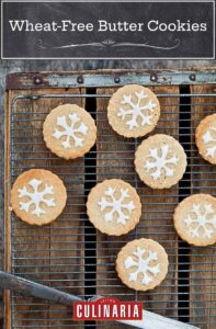 Round wheat-free butter cookies on a cooling rack set over a wooden board.