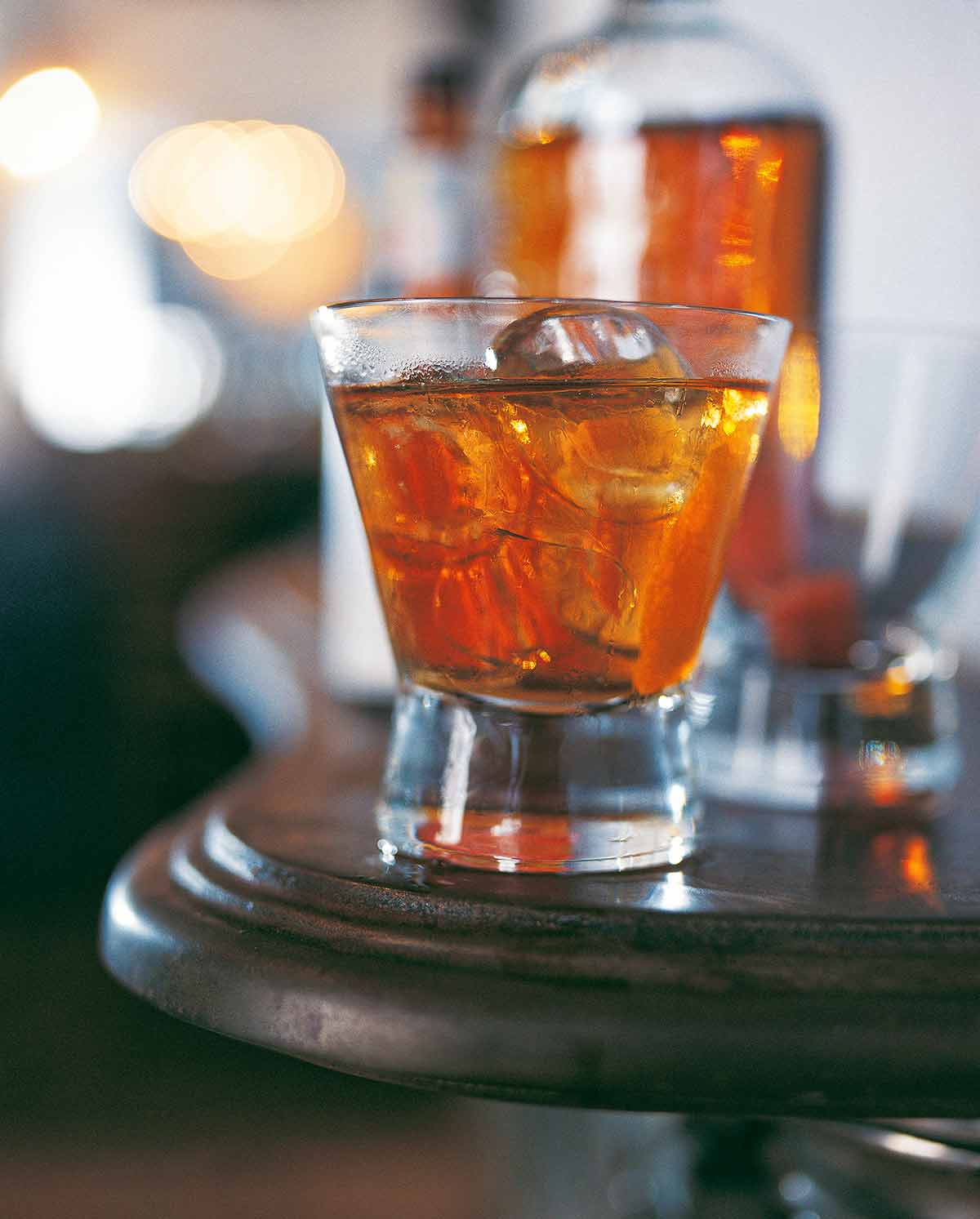 A highball glass filled with classic old-fashioned cocktail and large ice cubes.