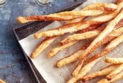 A layer of parmesan twists on a parchment-lined baking sheet.