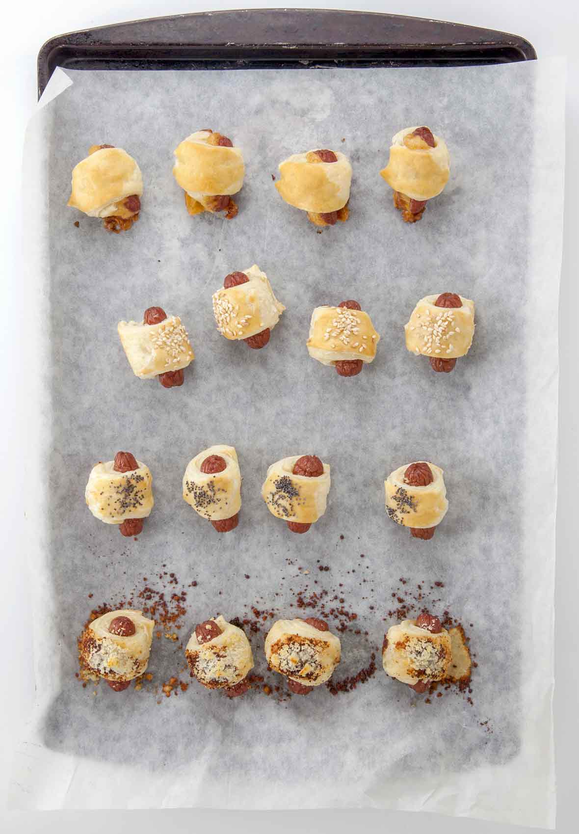 17 mini hot dogs wrapped in puff pastry on a parchment lined baking sheet