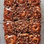 12 schnecken, pecan cinnamon buns, covered with pecan-caramel topping, and chopped pecans on a wire rack