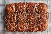12 schnecken, pecan cinnamon buns, covered with pecan-caramel topping, and chopped pecans on a wire rack