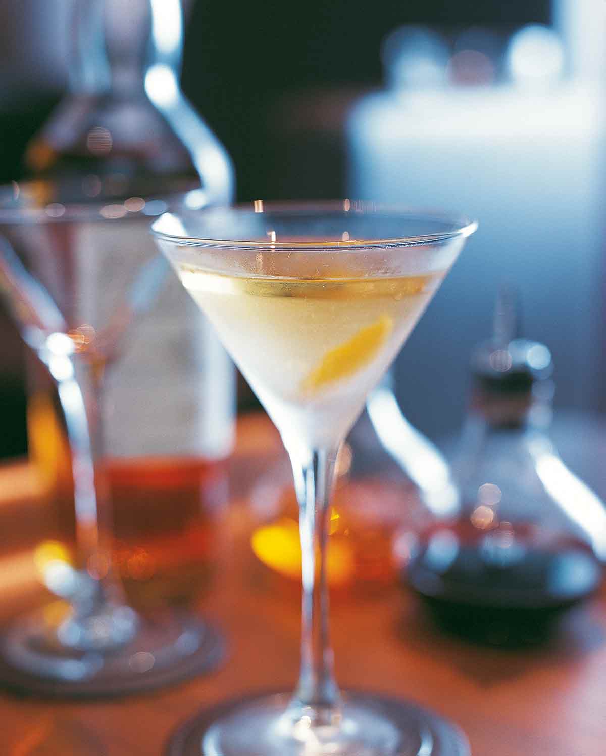 A stemmed cocktail glass on a bar filled with a smoky martini.