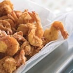 Pieces of bayou fried shrimp in a paper towel-lined bowl.