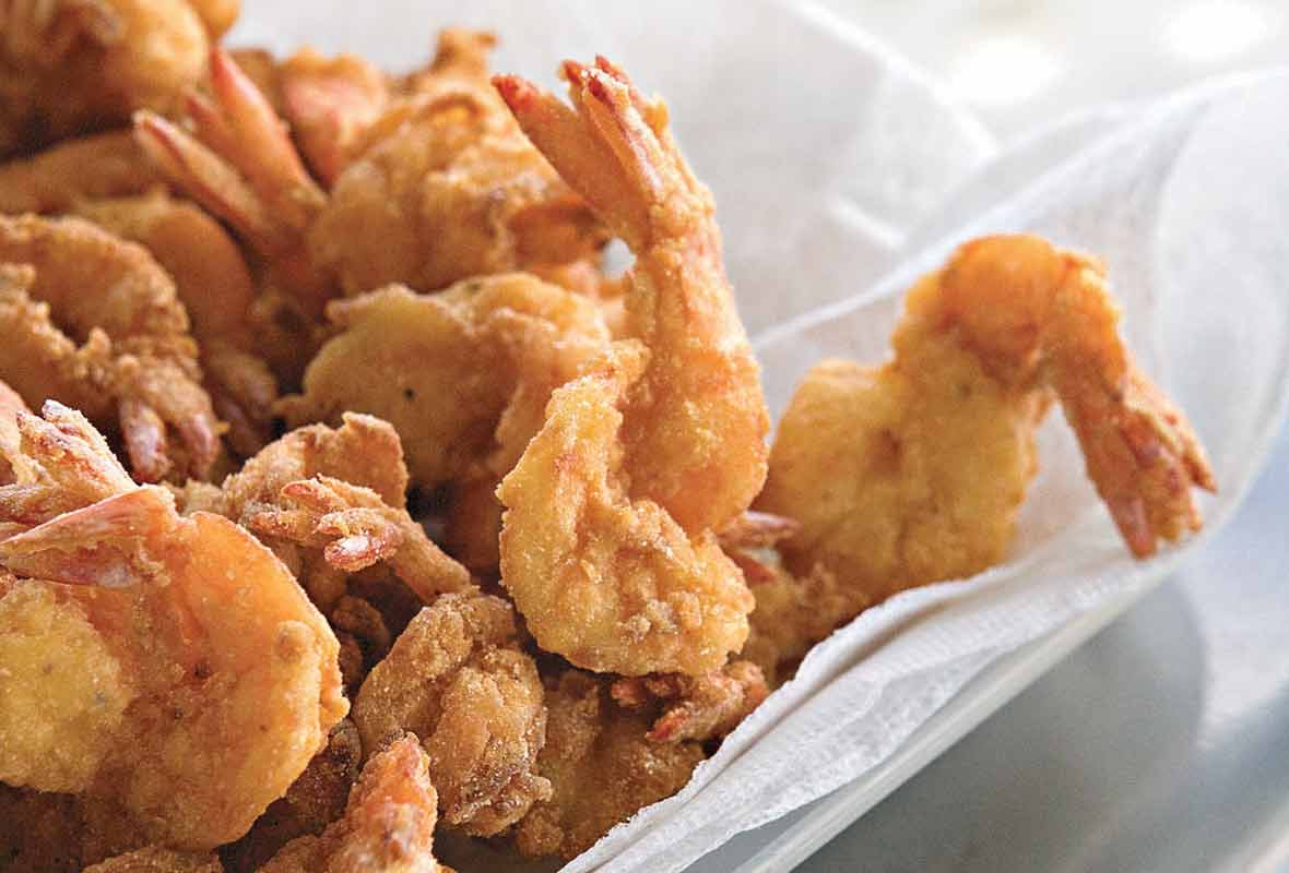Pieces of bayou fried shrimp in a paper towel-lined bowl.