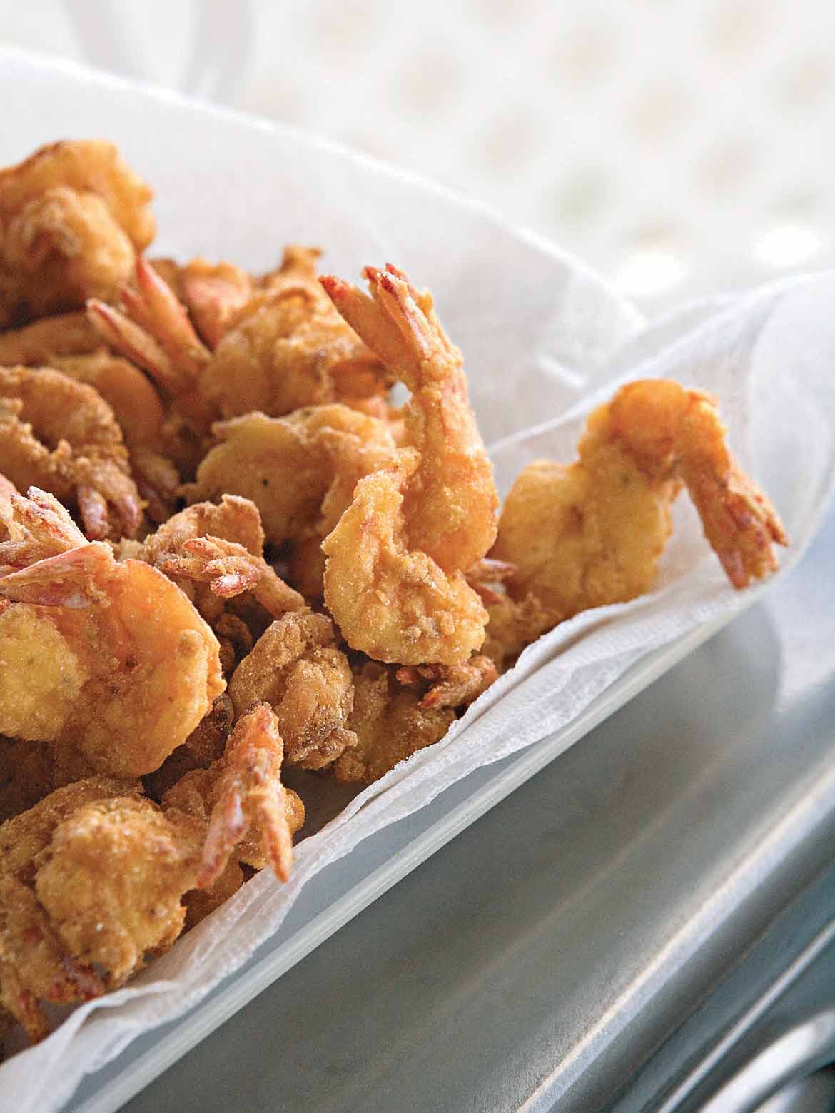 Pieces of bayou fried shrimp in a paper towel-lined bowl.