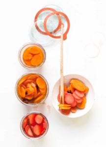 Three pickling jars with carrots and beets, a bowl on the side