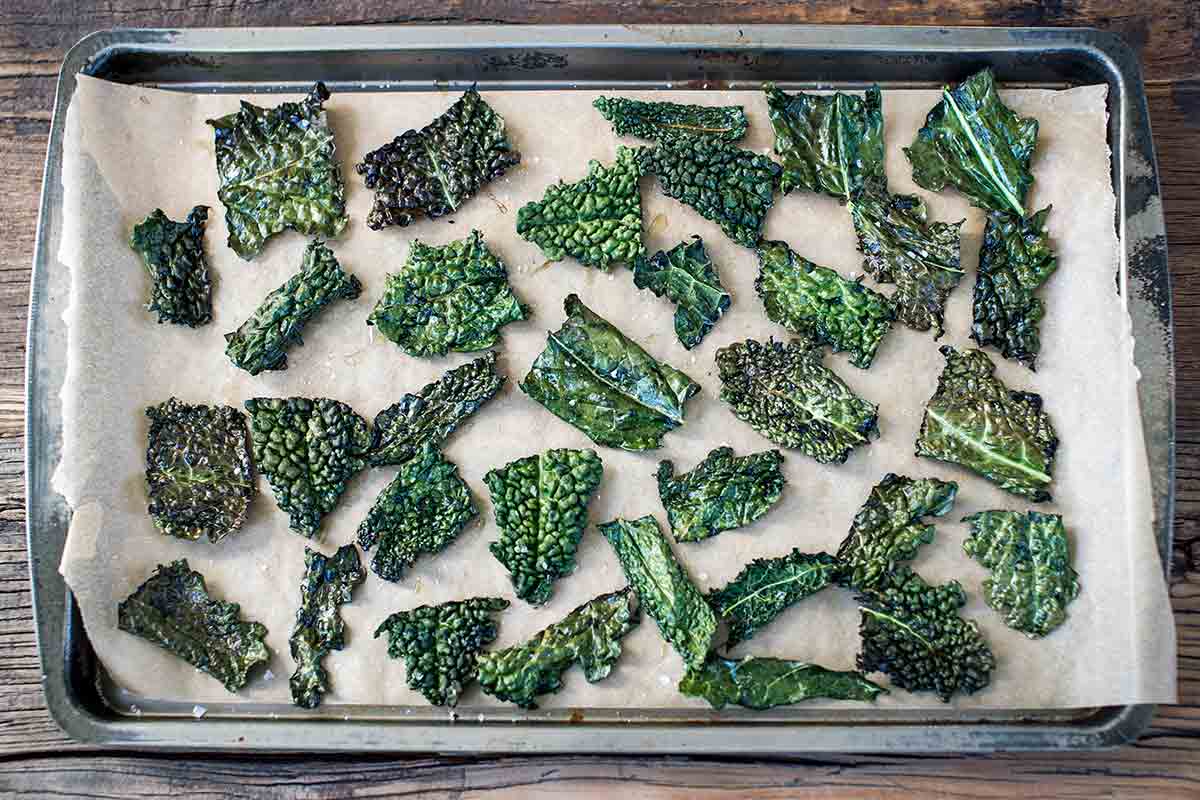 A rimmed baking sheet filled with crispy baked kale chips.