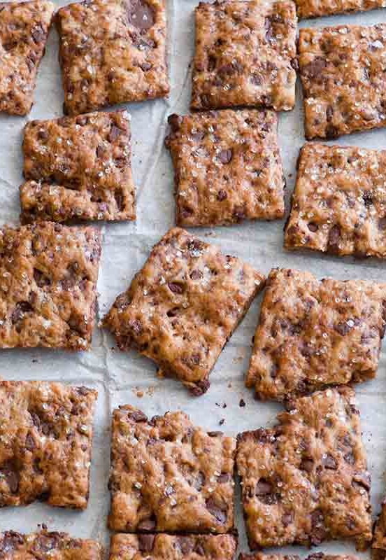 Squares of chocolate chip crisps on a sheet of parchment paper.