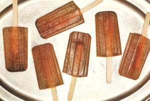 Six iced tea popsicles on a silver platter.