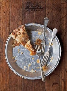 One slice of apple pie, made with flaky pie crust, in a metal pie plate with 3 forks.