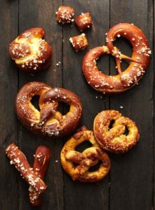 Soft pretzels of assorted shapes and sizes on a wooden surface.