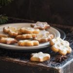 A white plate with a pile of sugar cookies coated in a champagne glaze.